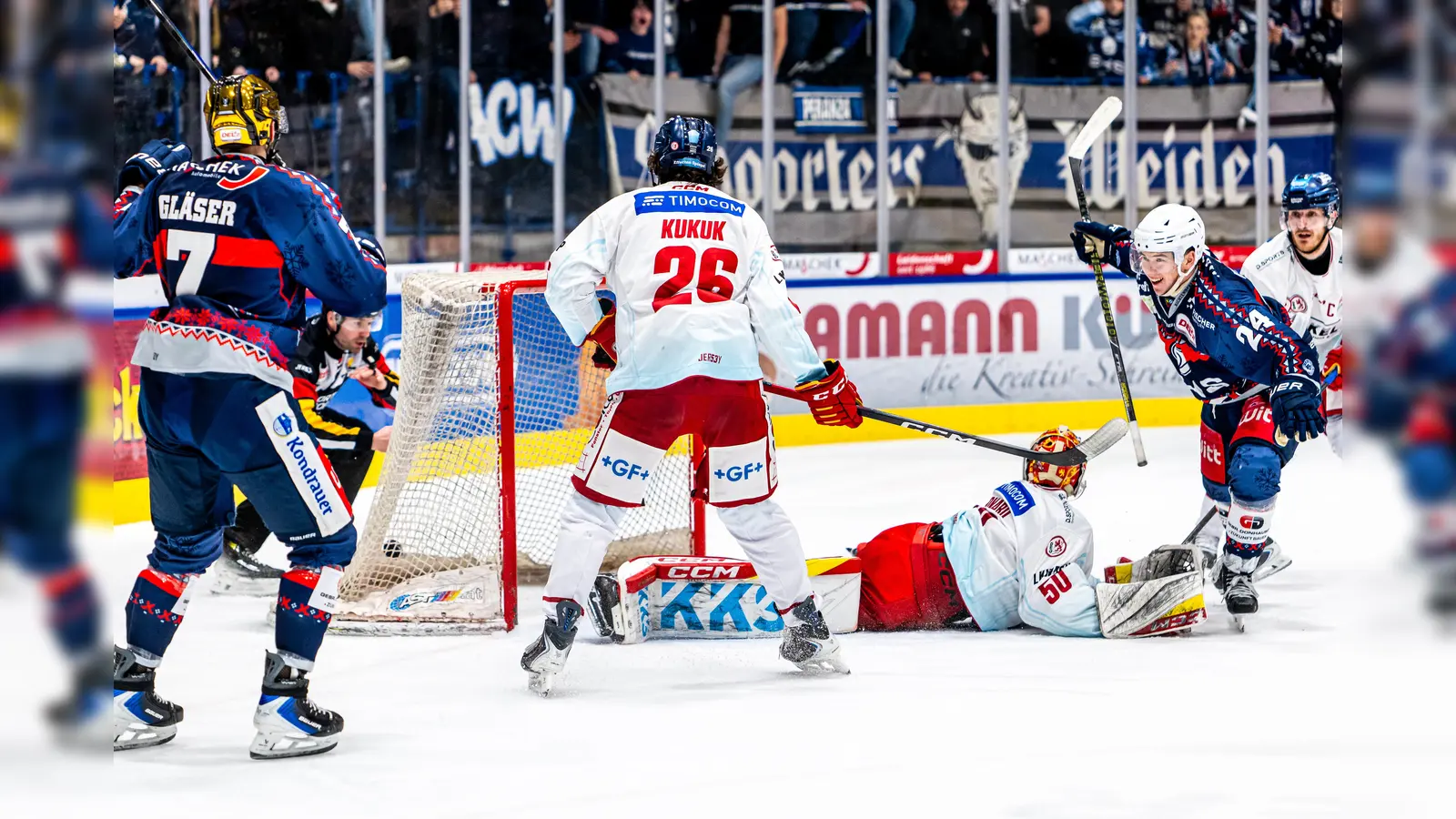 Gleich passiert es: Nachdem Paul Vinzens (rechts, blaues Trikot) in dieser Szene nach seinem Treffer zum Jubeln fahren will, verpasst ihm Moritz Kukuk (Mitte, weißes Trikot) einen Check mit dem Schläger ins Gesicht.  (Bild: Elke Englmaier)