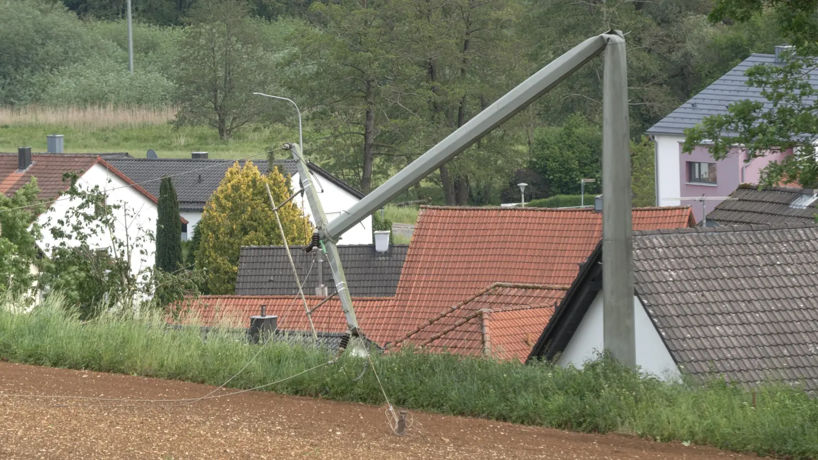Ein Leitungsmast in Deusmauer, Gemeindeteil der Stadt Velburg im Landkreis Neumarkt in der Oberpfalz, ist umgeknickt. (Bild:  Bernd März/ extremwetter.tv /dpa)