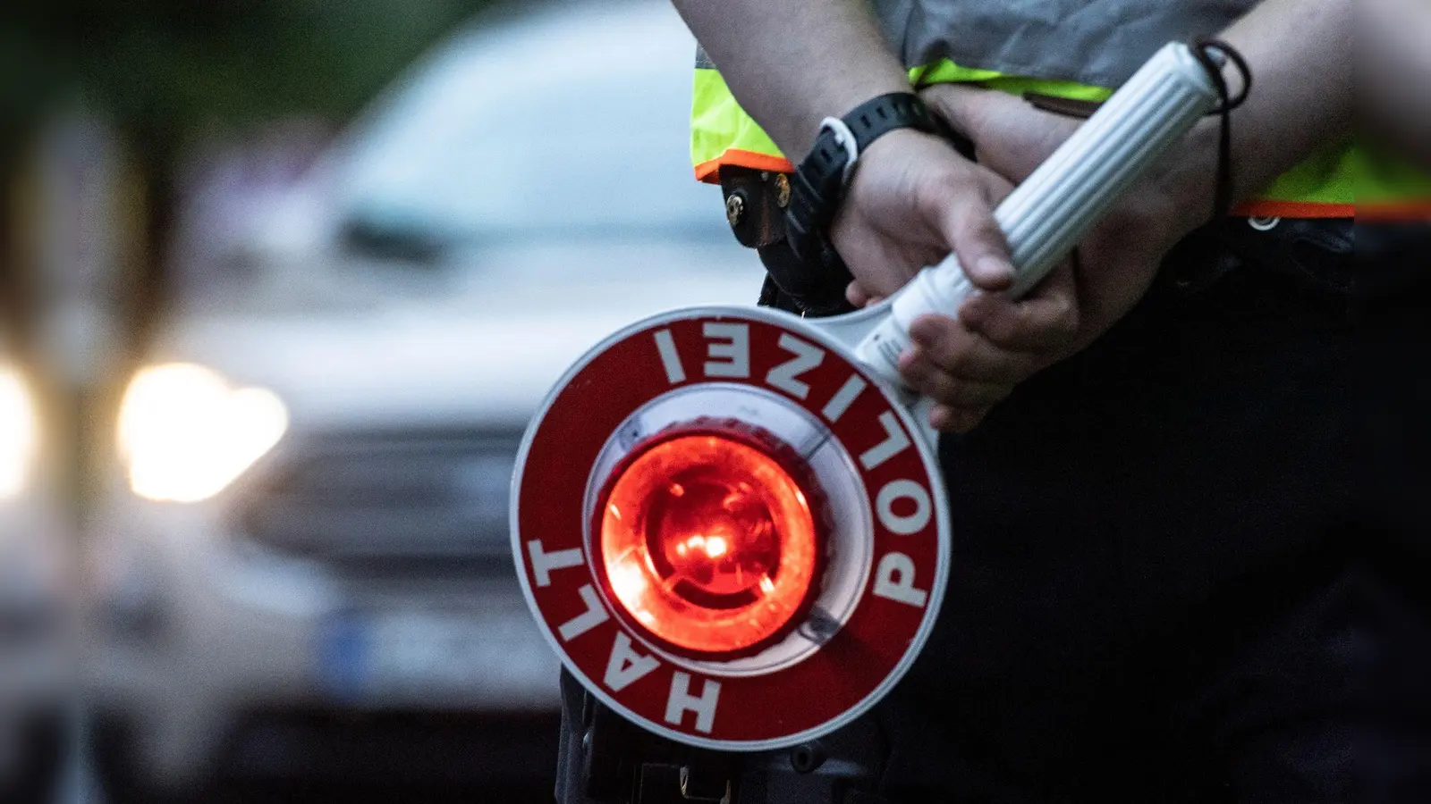 Ein Polizist hält bei einer Verkehrskontrolle eine Kelle in der Hand. (Symbolbild: Paul Zinken/dpa/ZB/)