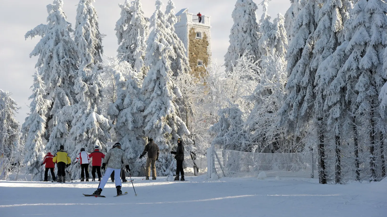 Skifahrer laufen auf dem Ochsenkopf bei Bischofsgrün im Fichtelgebirge am Asenturm vorbei.  (Archivbild: David Ebener, dpa)