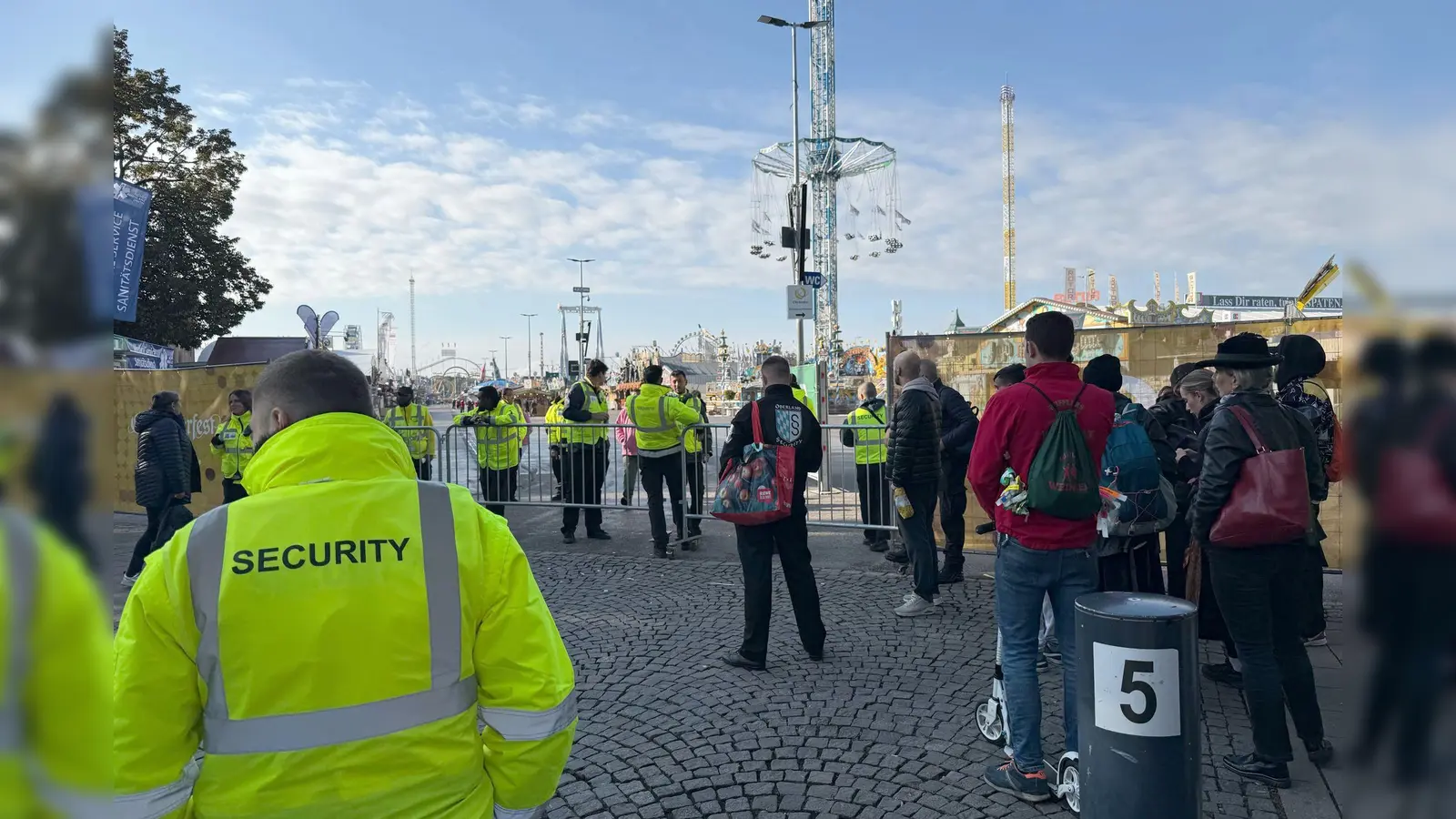 Menschen stehen an einer Absperrung an einem Eingang zum Oktoberfest. Das Münchner Oktoberfest bleibt wegen einer Sprengstoffdrohung bis mindestens 17.00 Uhr geschlossen. (Bild: Manuel Schwarz/dpa)