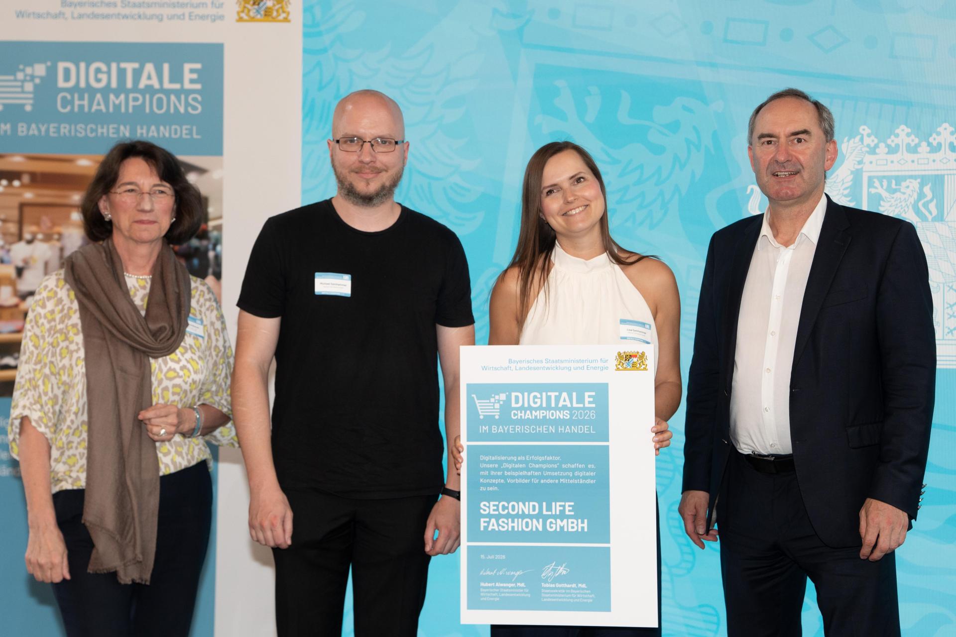 Lisa Samhammers (zweite von rechts) Unternehmen Second Life Fashion GmbH wurde beim Wettbewerb „Digitale Champions im bayerischen Handel 2026“ ausgezeichnet. Bayerns Wirtschaftsminister Huber Aiwanger (rechts) übergab die Urkunde an die Preisträgerinnen und Preisträger. (Bild: Wirtschaftsministerium/Bastian Brummer)